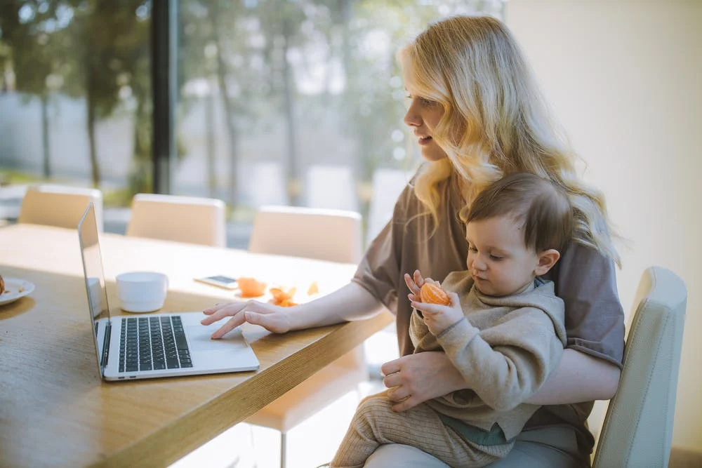 https://www.pexels.com/photo/woman-carrying-her-baby-and-working-on-a-laptop-4079281/